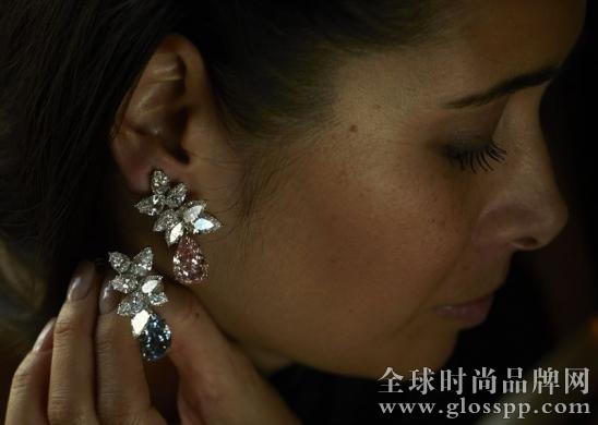 File picture of a Christie's staff member holding a Bulgari pear-shaped coloured diamond ear-pendants d in Geneva